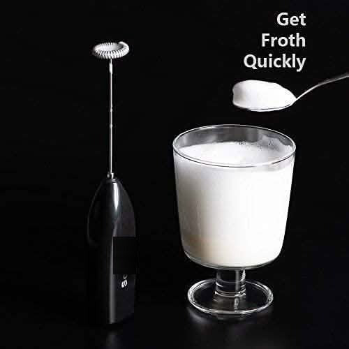 Handheld milk frother beside a tall glass of frothed milk on a dark background