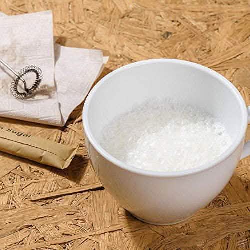 White cup filled with thick frothed milk on a wooden table