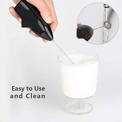 Hand using the milk frother in a glass of milk with a close-up of the whisk head